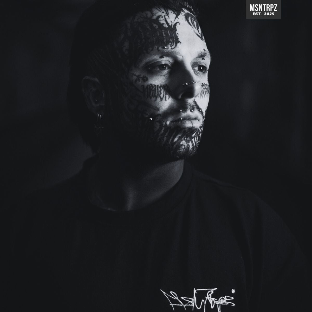 Dunkles Schwarz-Weiß-Porträt eines tätowierten Mannes mit intensiver Mimik, Sinnbild für innere Stärke, Abgrenzung vom Mainstream und die MISANTHROPZ® Philosophie. Ausdrucksstarkes Visual der Premium German Streetwear Brand MSNTRPZ.