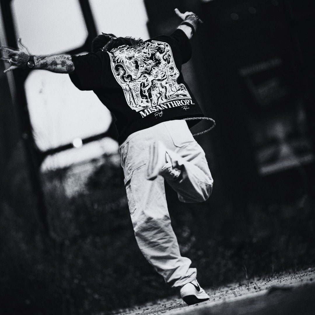 MSNTRPZ® MISANTHROPZ® Noir-Aufnahme eines springenden Models im schwarzen Backprint Art Shirt mit ikonischem MISANTHROPZ® Motiv | Premium German Streetwear