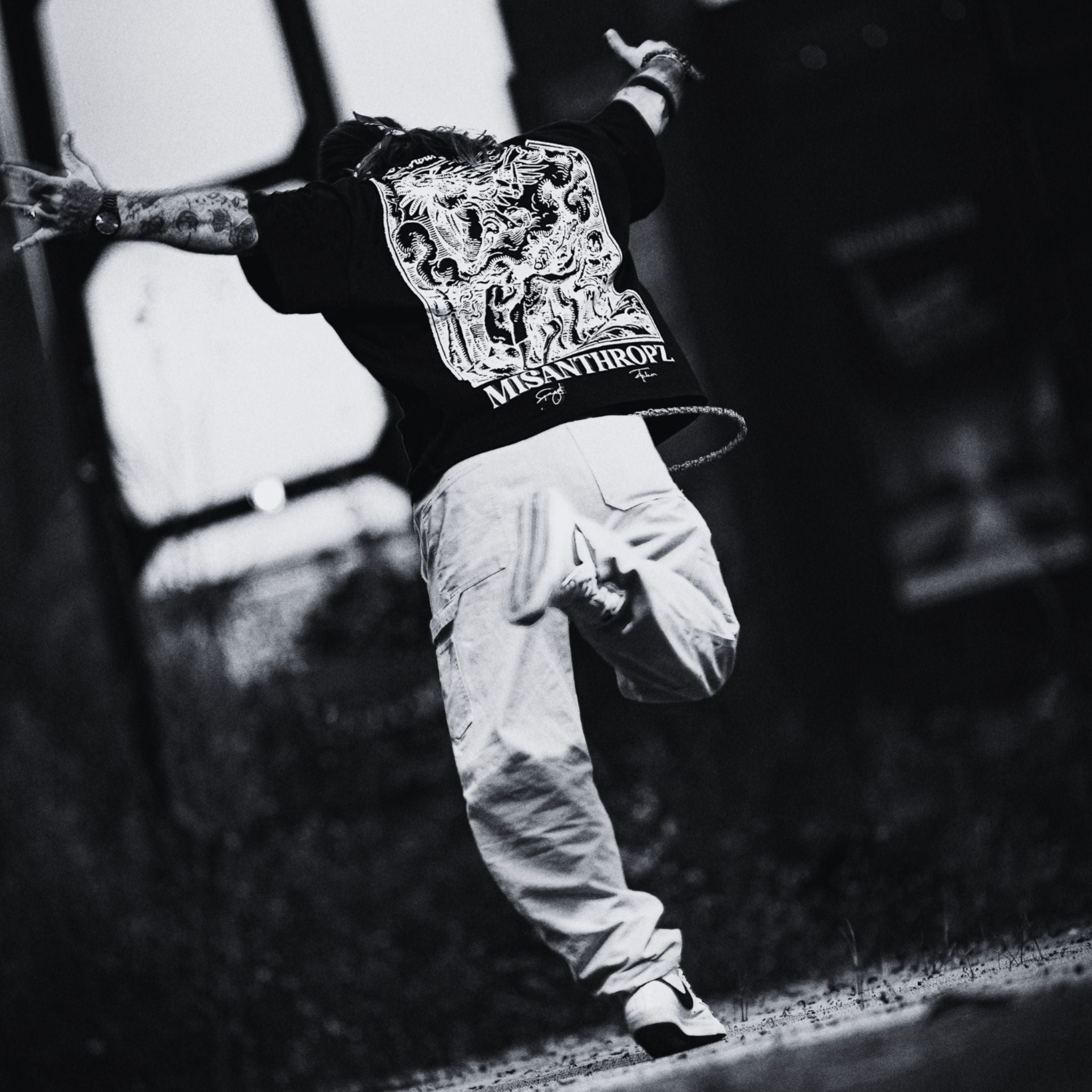 MSNTRPZ® MISANTHROPZ® Noir-Aufnahme eines springenden Models im schwarzen Backprint Art Shirt mit ikonischem MISANTHROPZ® Motiv | Premium German Streetwear