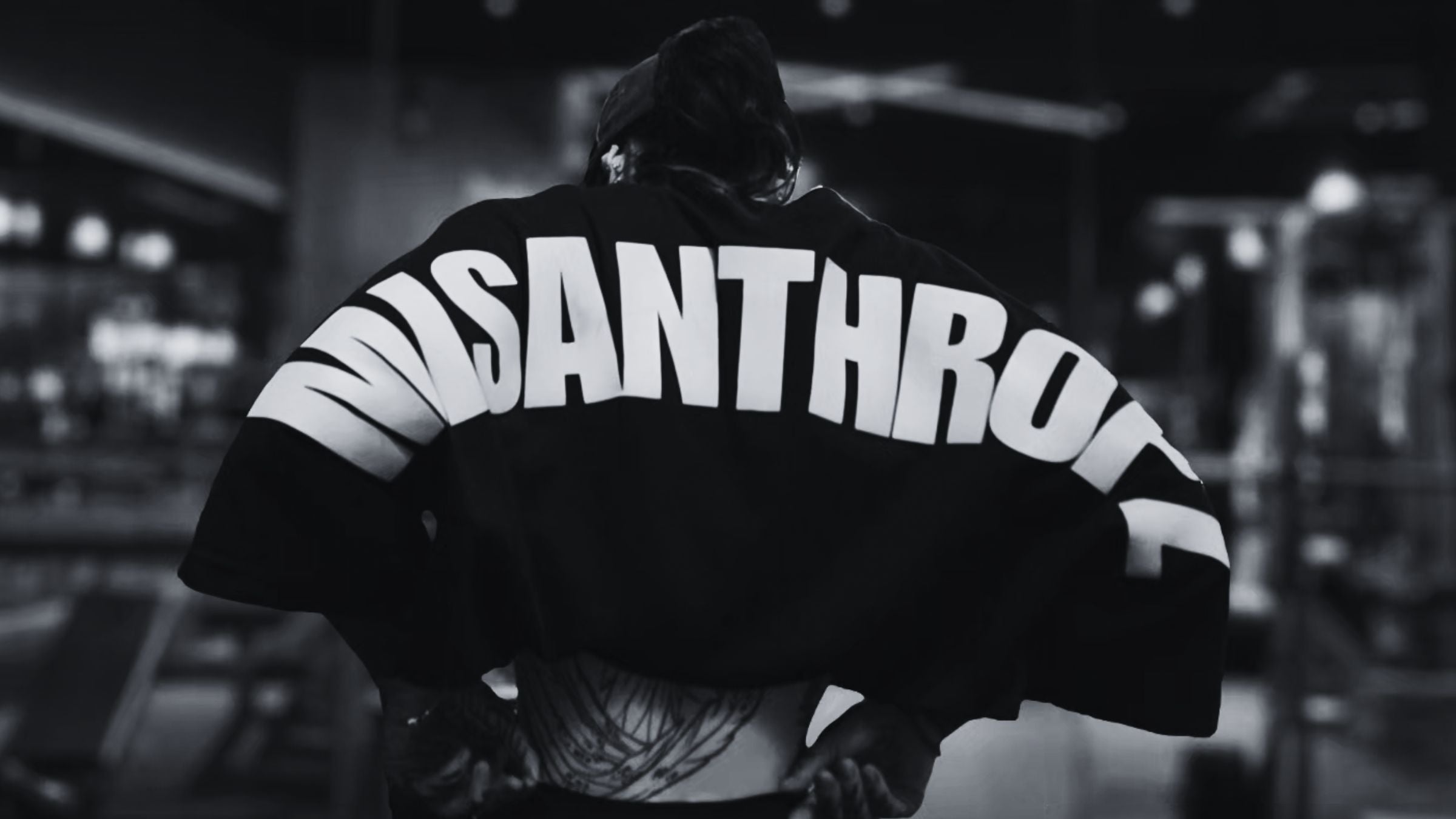 MSNTRPZ® MISANTHROPZ® Noir-Backshot eines tätowierten Models im Premium-Streetwear-Shirt mit markantem „MISANTHROPZ“ Rückenprint, aufgenommen in einer rauen Gym-Atmosphäre – Premium German Streetwear, roh, kompromisslos und authentisch.