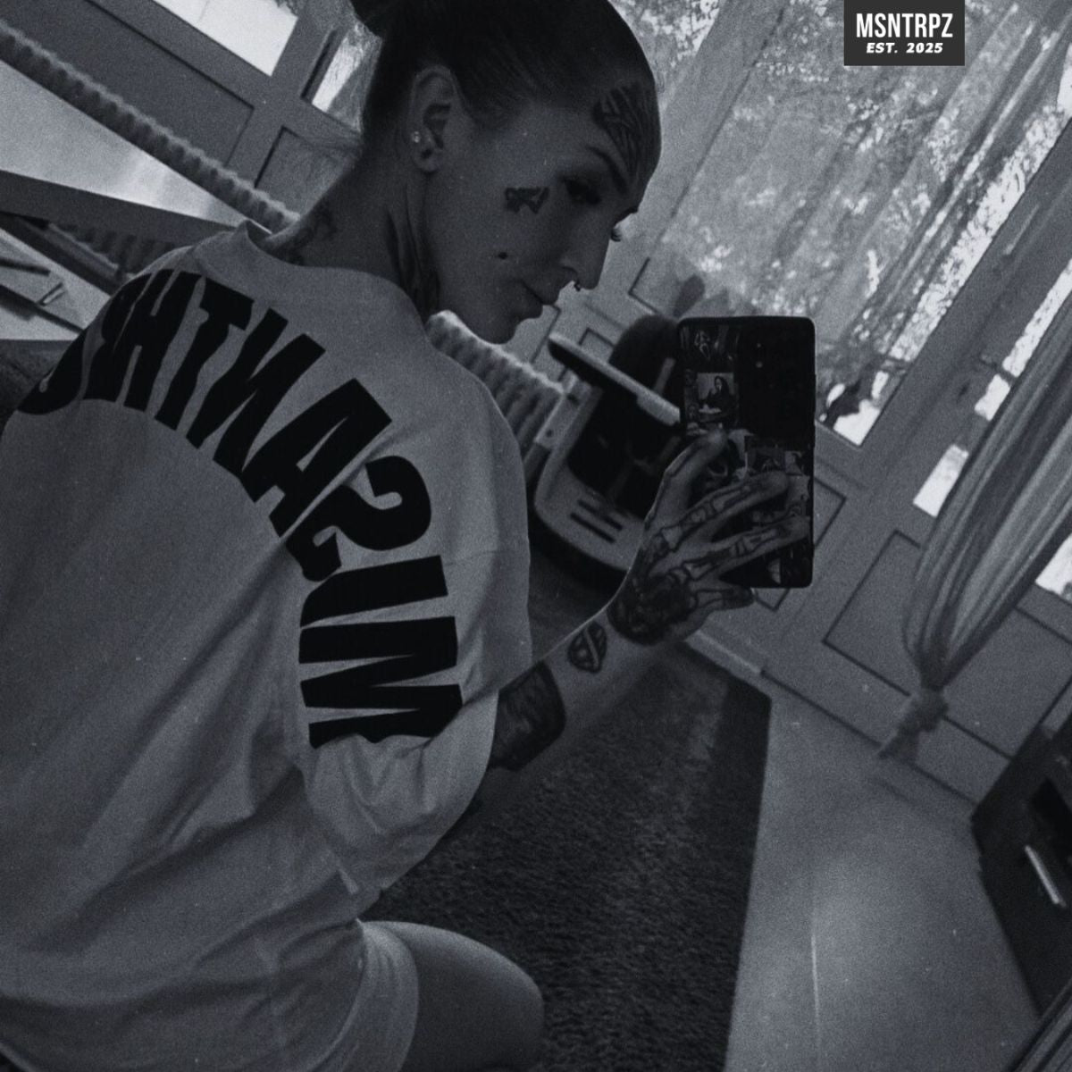 MSNTRPZ® MISANTHROPZ® Noir-Mirror-Shot eines Models, das ein weißes Premium-Shirt mit großem MISANTHROPZ® Backprint trägt; urbaner Indoor-Streetwear-Look | Premium German Streetwear