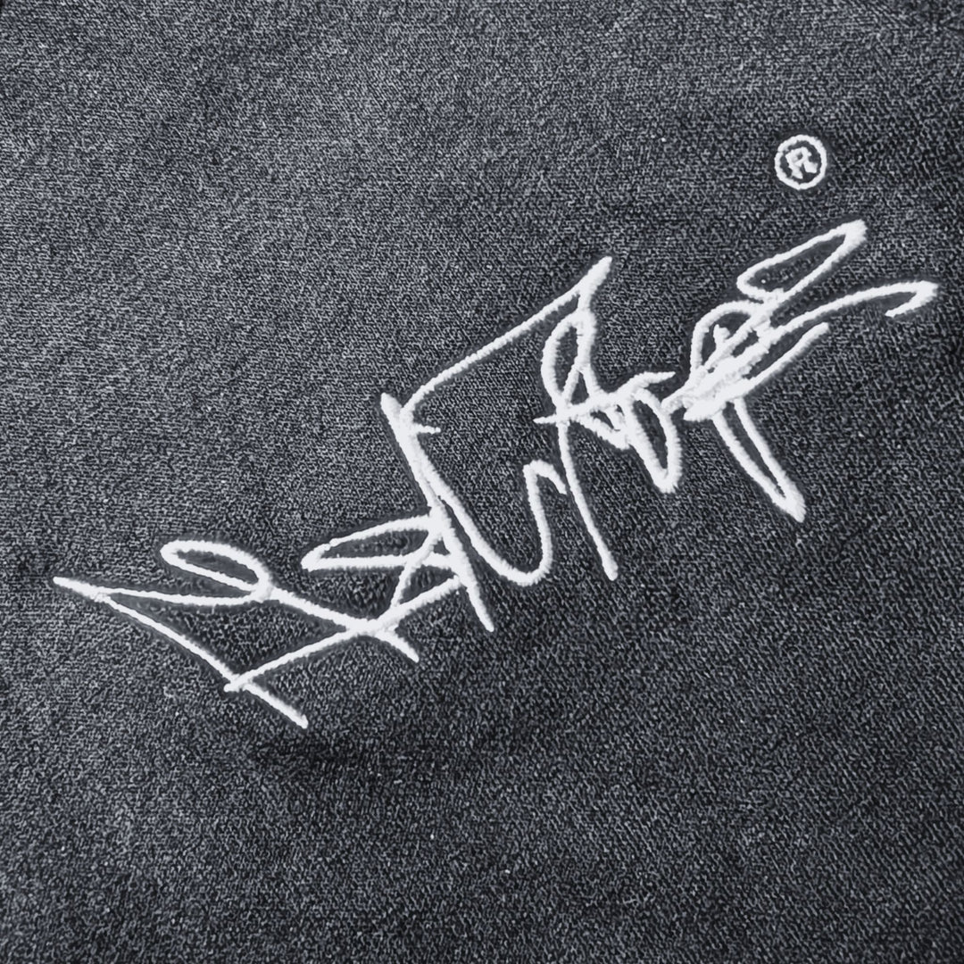 Nahaufnahme des gestickten MSNTRPZ® MISANTHROPZ® Signature-Logos auf dunklem Stoff im Noir-Stil; hochwertige Stickerei und strukturierte Textur | Premium German Streetwear