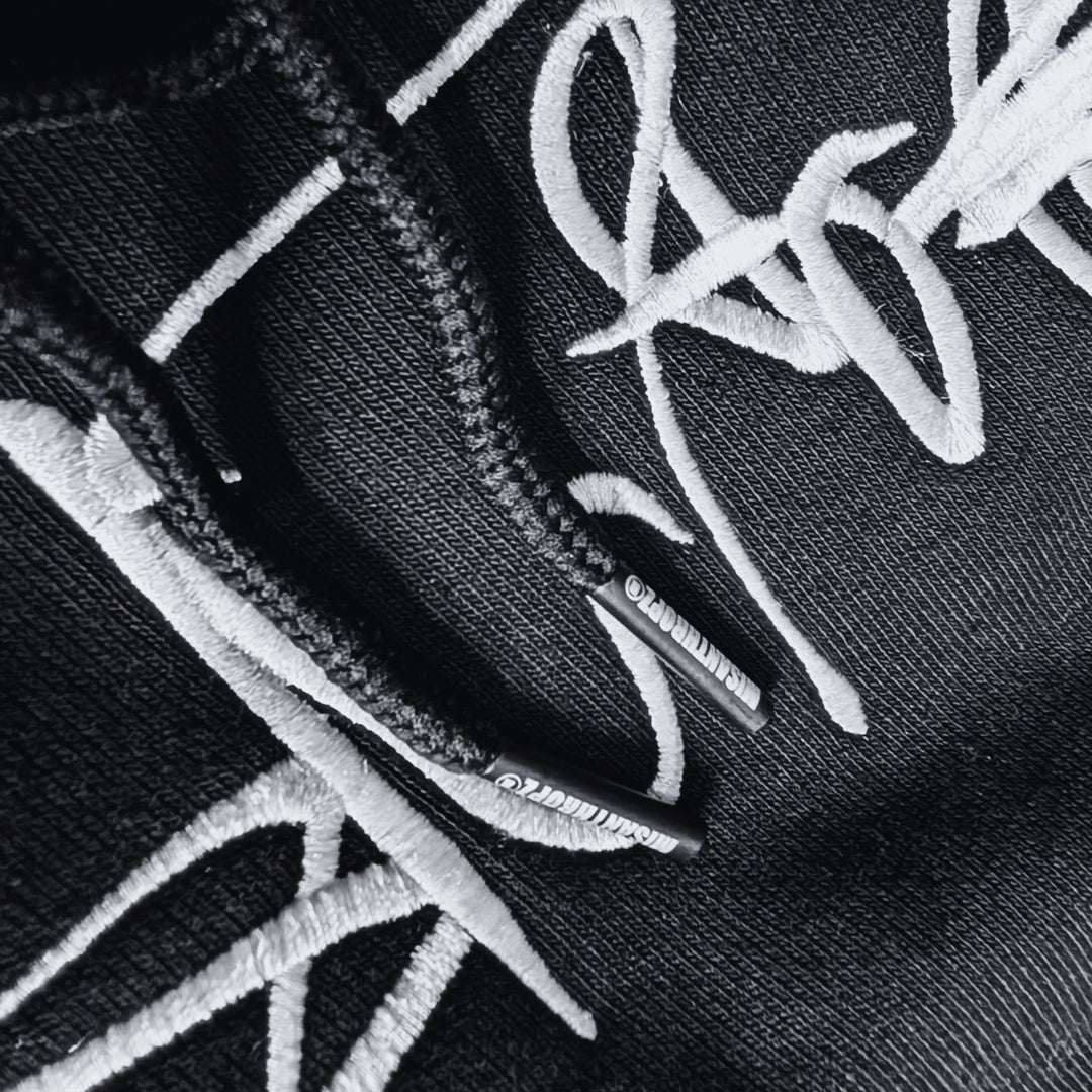 Detailaufnahme des MSNTRPZ® MISANTHROPZ® Hoodies mit gesticktem Signature-Schriftzug und markenprägten Kordelenden; hochwertige Textur im Noir-Stil | Premium German Streetwear