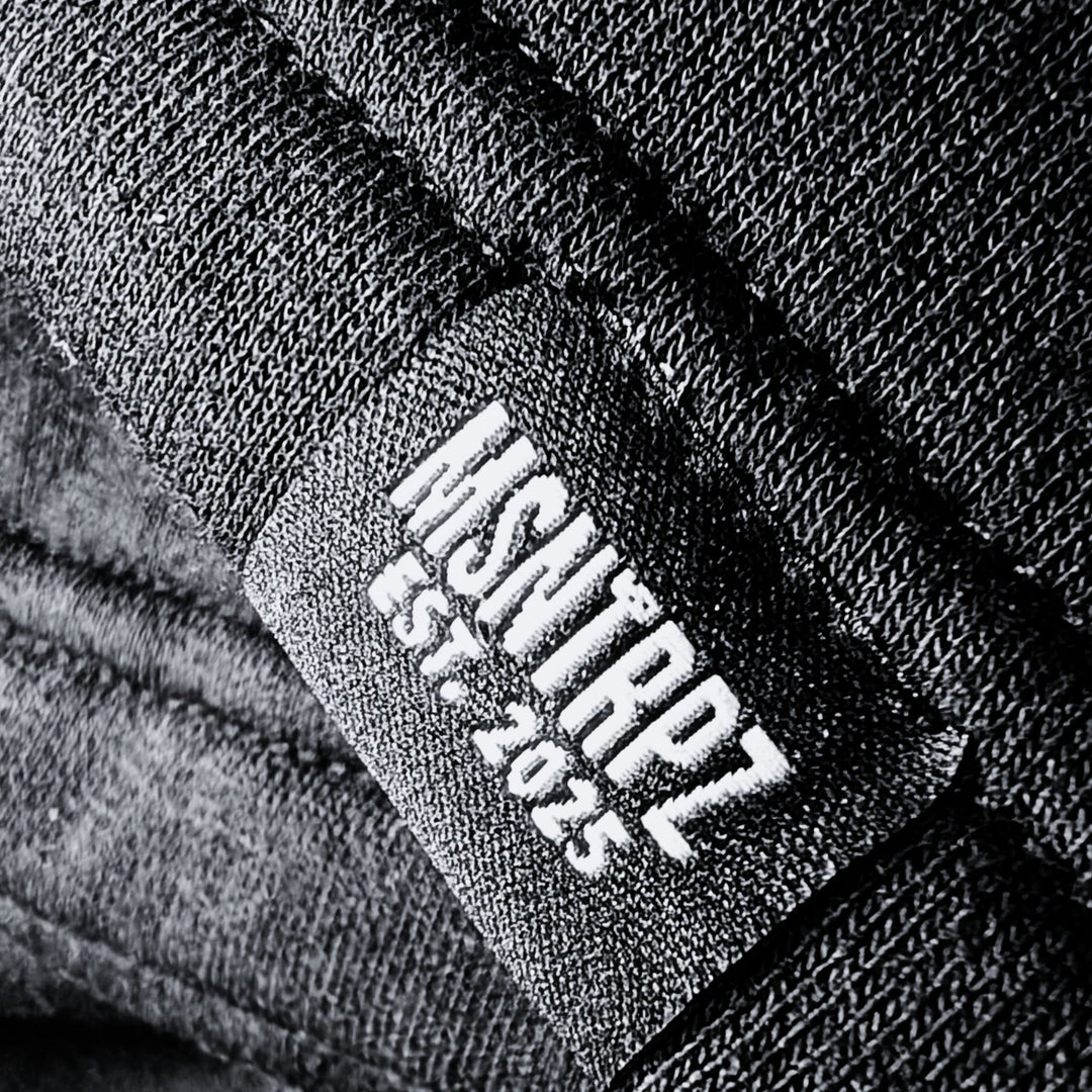 Nahaufnahme eines schwarzen MSNTRPZ® Labels mit weißer Stickschrift „MSNTRPZ EST. 2025“ auf hochwertigem Stoff; Premium German Streetwear im Noir-Stil
