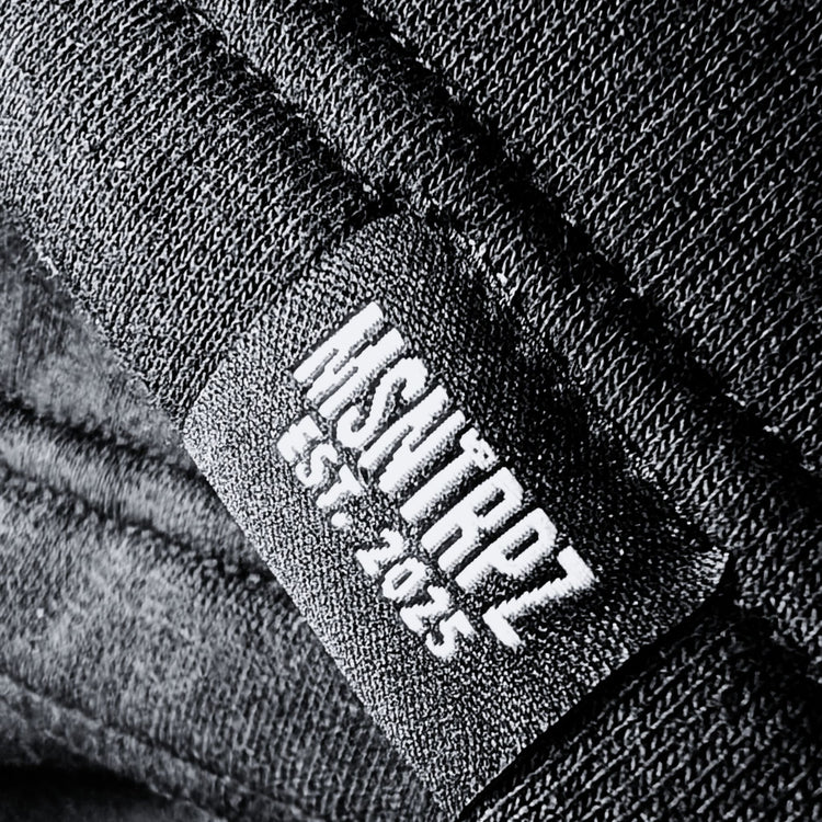 Nahaufnahme eines schwarzen MSNTRPZ® Labels mit weißer Stickschrift „MSNTRPZ EST. 2025“ auf hochwertigem Stoff; Premium German Streetwear im Noir-Stil