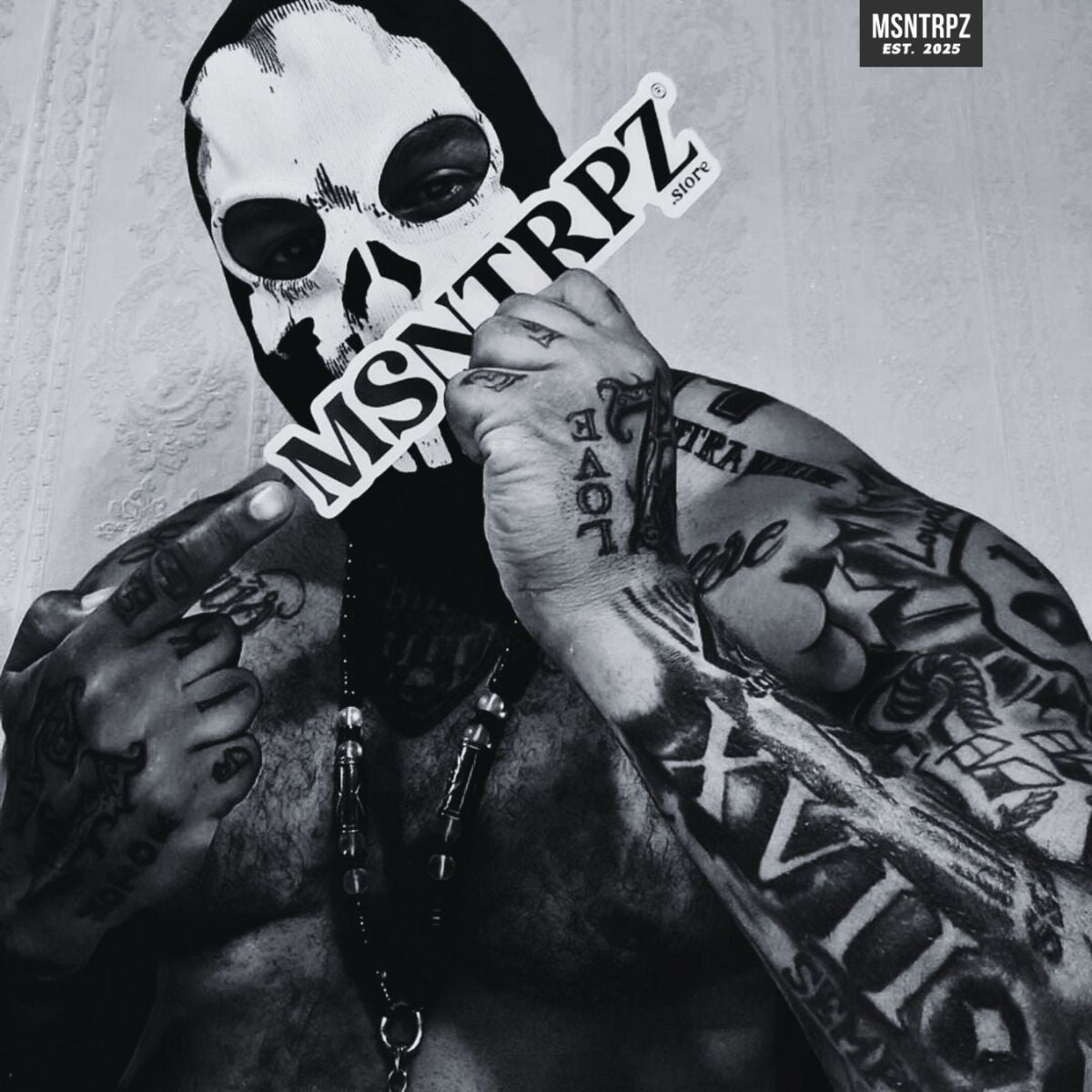 MSNTRPZ® MISANTHROPZ® Noir-Portrait eines tätowierten Models mit Skull-Maske, der ein MSNTRPZ® Logo hält | Premium German Streetwear