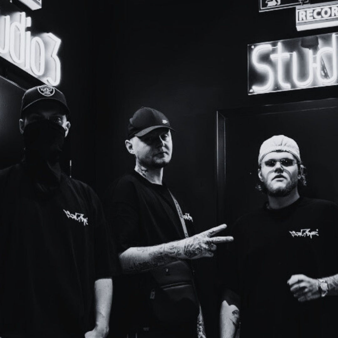 MSNTRPZ® MISANTHROPZ® Noir-Aufnahme von drei Models im Studio, komplett in schwarzer Premium-Streetwear gekleidet; urbane Tattoos, Masken- und Cap-Styles verstärken die düstere Premium-German-Streetwear-Ästhetik.