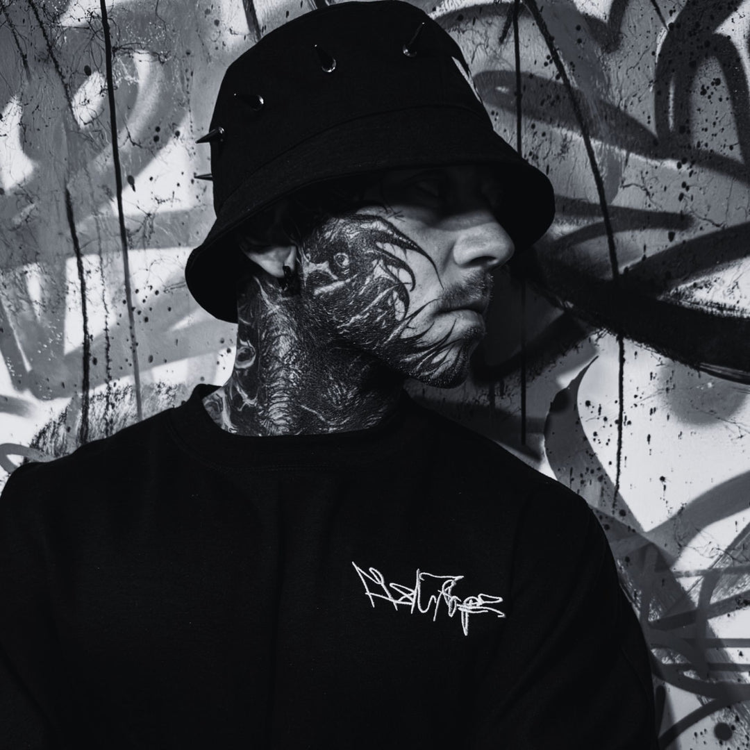 MSNTRPZ® MISANTHROPZ® Noir-Portrait eines tätowierten Models im schwarzen Premium Streetwear-Look vor Graffiti-Wand | Premium German Streetwear
