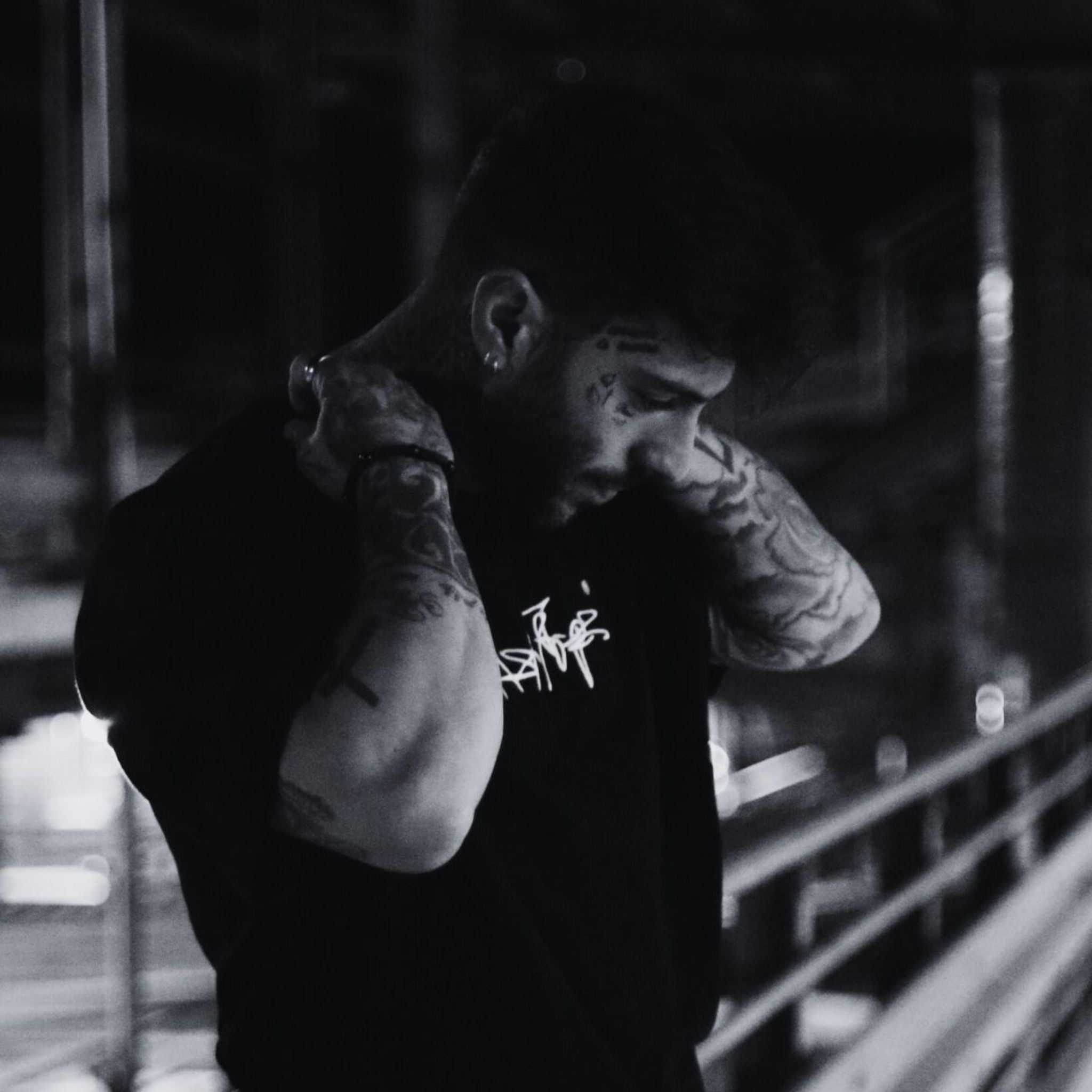 MSNTRPZ® MISANTHROPZ® Nachtaufnahme eines tätowierten Models im schwarzen Premium-Streetwear-Shirt, im charakteristischen Noir-Look der Premium German Streetwear-Kollektion.